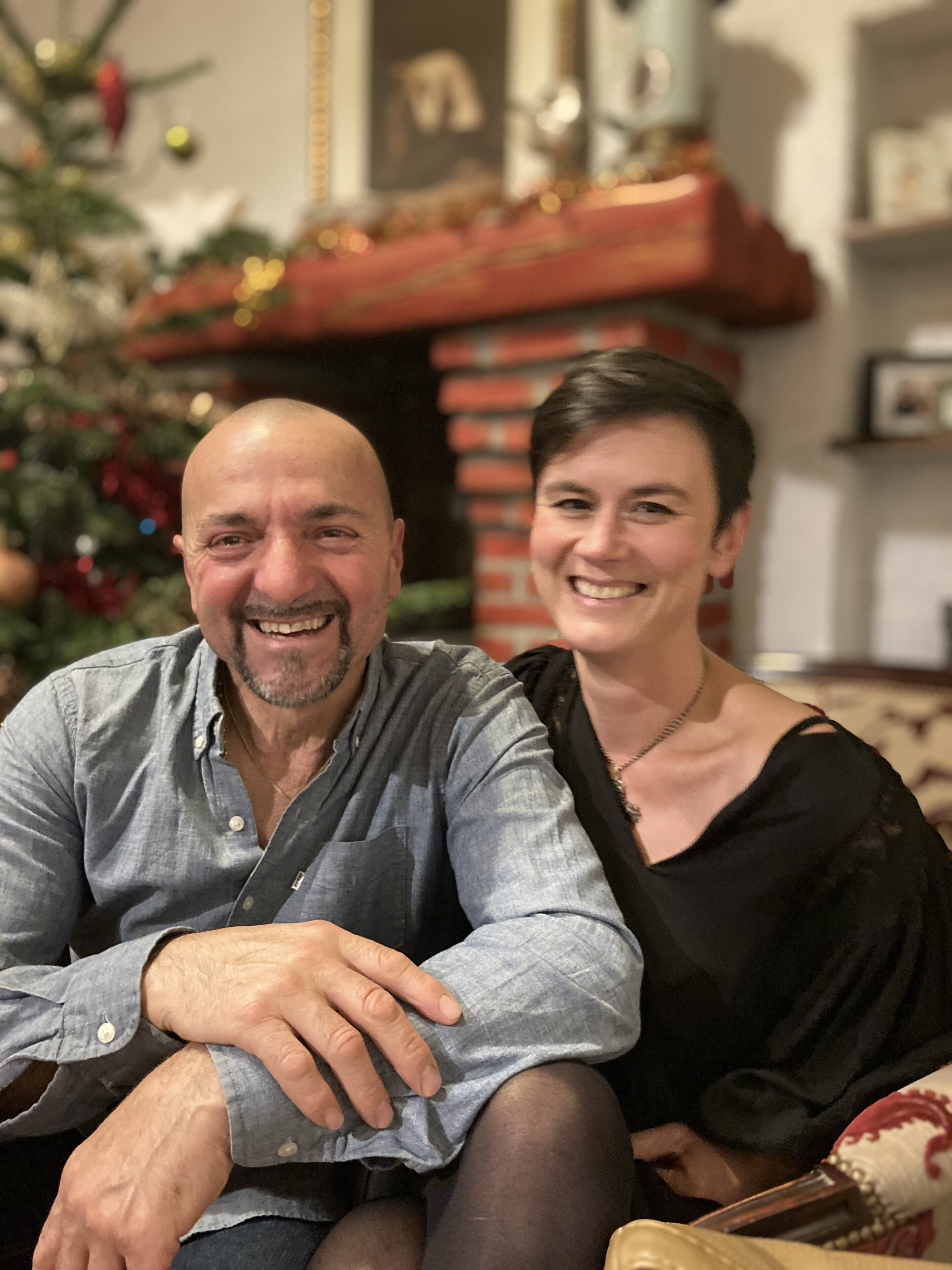 Audrey & Paul souriant devant la cheminée décorée pour Noël au Mas Picagnol, gîte de groupe à Oms dans les Pyrénées-Orientales.